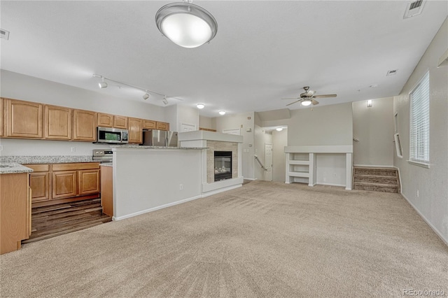 5255 Memphis St Unit 1009, Denver, CO 80239 - unfurnished living room with a ceiling fan, dark carpet, stairs, and a tiled fireplace