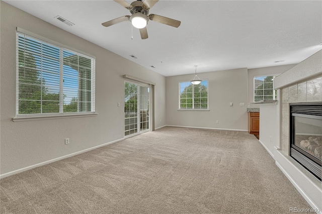 5255 Memphis St Unit 1009, Denver, CO 80239 - unfurnished living room with healthy amount of natural light, a fireplace, light colored carpet, and a ceiling fan