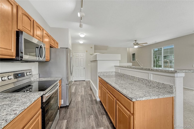 5255 Memphis St Unit 1009, Denver, CO 80239 - kitchen featuring stainless steel appliances, dark wood-style floors, a ceiling fan, light stone countertops, and track lighting