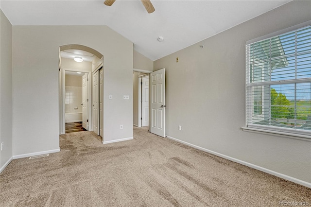 5255 Memphis St Unit 1009, Denver, CO 80239 - unfurnished bedroom featuring arched walkways, carpet, ensuite bathroom, lofted ceiling, and ceiling fan