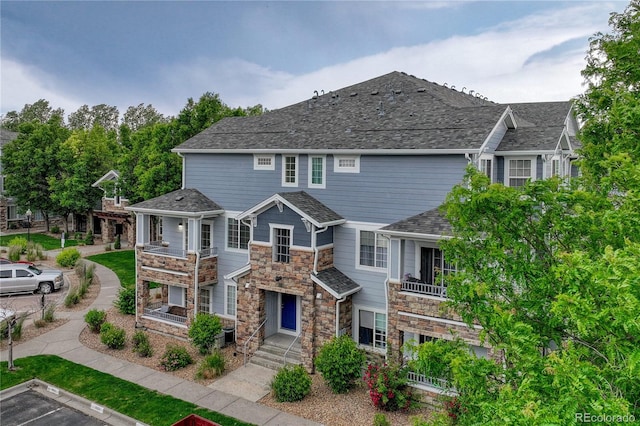 5255 Memphis St Unit 1009, Denver, CO 80239 - view of front facade with a balcony, stone siding, and uncovered parking