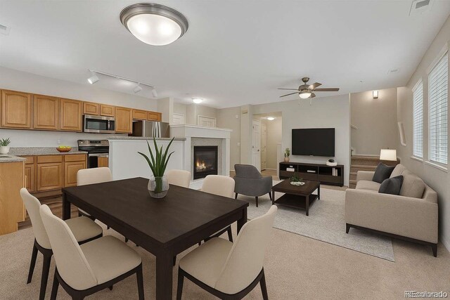 5255 Memphis St Unit 1009, Denver, CO 80239 - dining room featuring light carpet, ceiling fan, and a lit fireplace