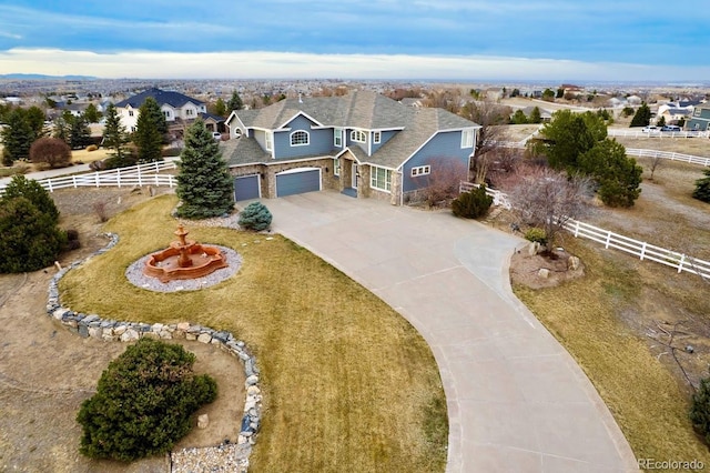 view of front of property with fence, a residential view, concrete driveway, a garage, and stone siding