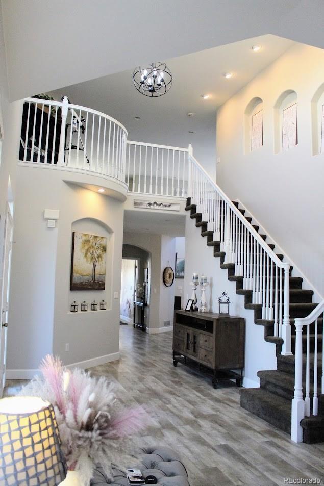 staircase with baseboards, a notable chandelier, and a towering ceiling