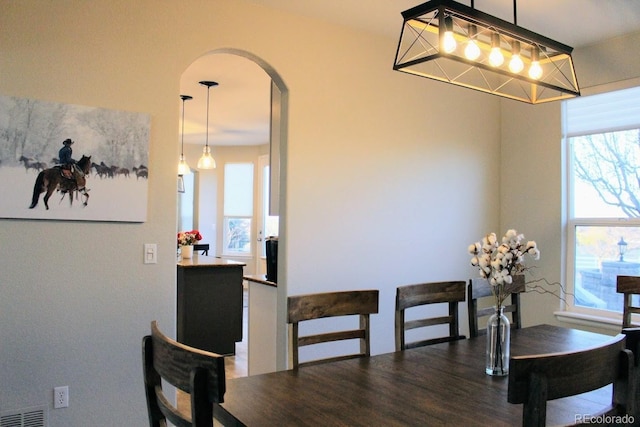 dining area featuring wood finished floors, visible vents, and arched walkways