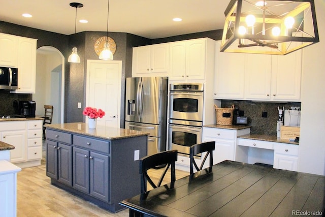 kitchen featuring arched walkways, a notable chandelier, white cabinets, and stainless steel appliances