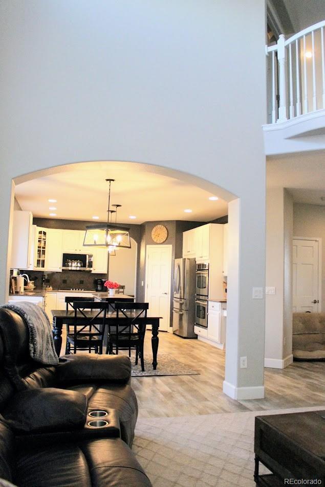 living area with baseboards, arched walkways, and a towering ceiling