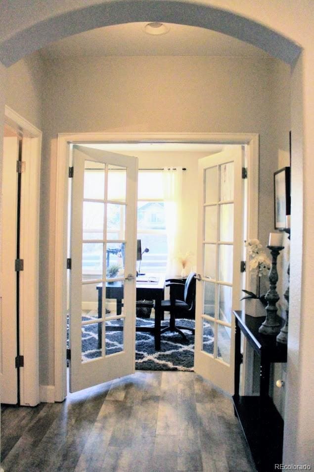 doorway to outside featuring wood finished floors, french doors, and arched walkways