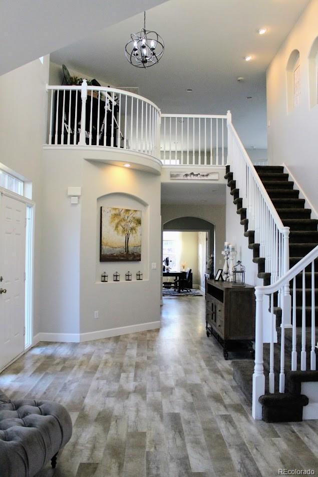 entryway featuring wood finished floors, baseboards, arched walkways, stairs, and a towering ceiling