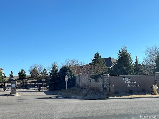 view of street with a gate, traffic signs, sidewalks, curbs, and a gated entry