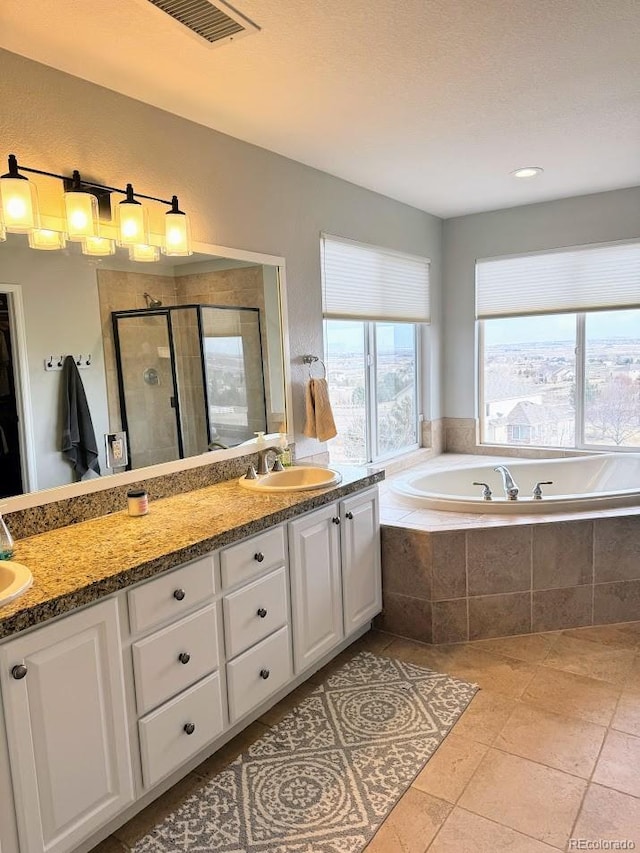 full bathroom featuring visible vents, double vanity, a stall shower, a sink, and a garden tub