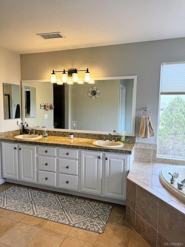 bathroom with a sink, visible vents, a textured ceiling, and double vanity