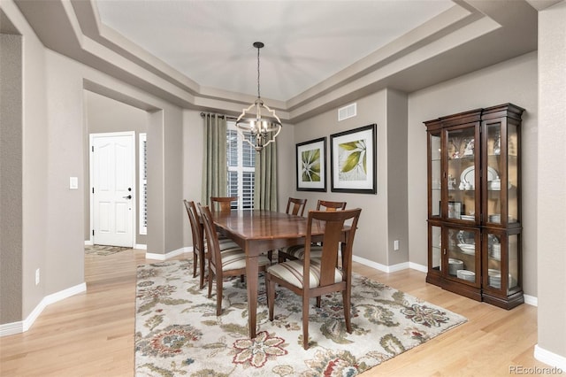 6690 S Fenton St, Littleton, CO 80123 - dining room featuring visible vents, a notable chandelier, a raised ceiling, and light wood-style floors
