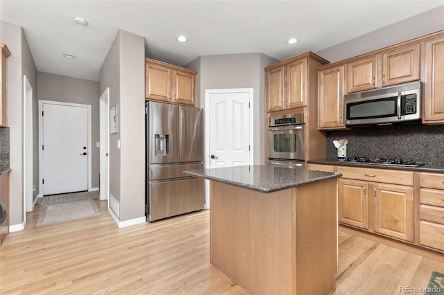 6690 S Fenton St, Littleton, CO 80123 - kitchen featuring appliances with stainless steel finishes, light wood-style floors, dark stone countertops, decorative backsplash, and a kitchen island