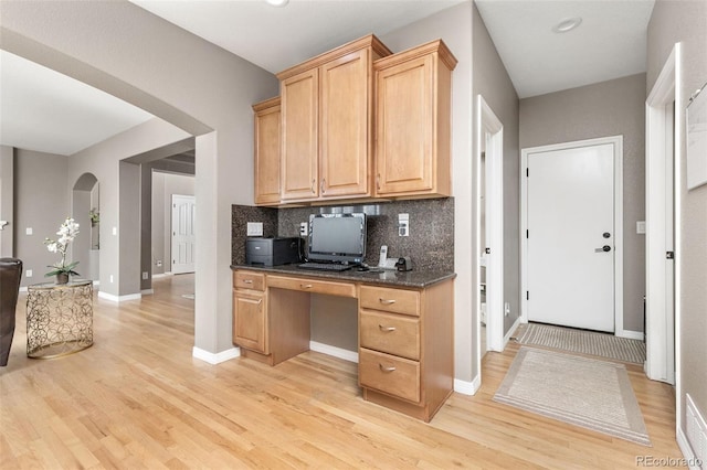 6690 S Fenton St, Littleton, CO 80123 - kitchen with arched walkways, light wood-style floors, dark countertops, and decorative backsplash