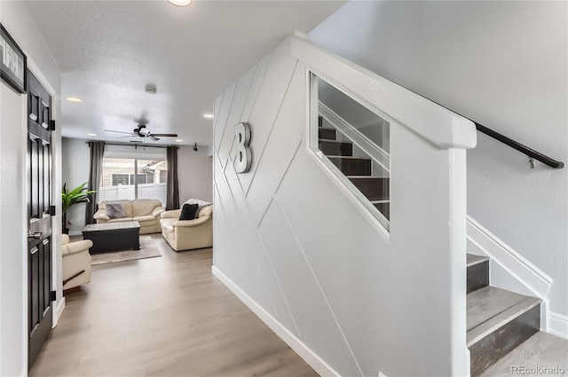 staircase with a textured ceiling, hardwood / wood-style flooring, and ceiling fan