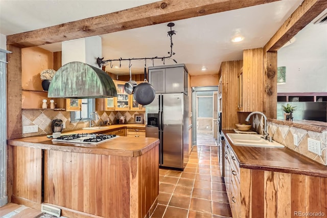 kitchen featuring appliances with stainless steel finishes, tasteful backsplash, kitchen peninsula, beam ceiling, and sink