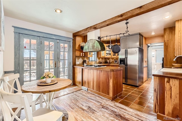 kitchen featuring dark tile patterned flooring, sink, kitchen peninsula, backsplash, and appliances with stainless steel finishes