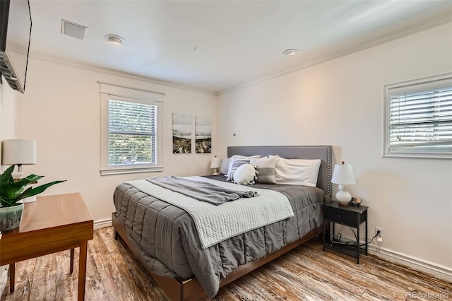 bedroom with multiple windows, hardwood / wood-style floors, and crown molding