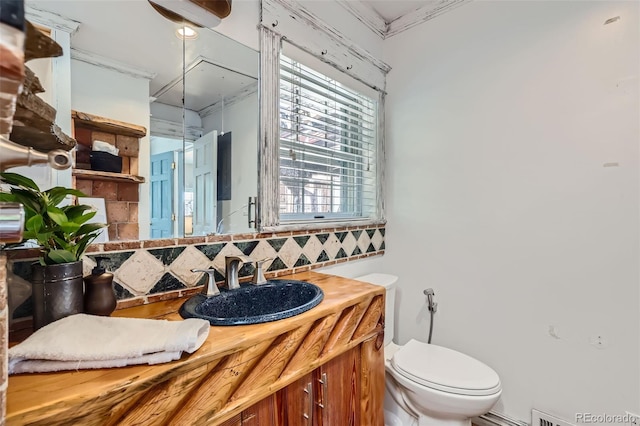 bathroom with ornamental molding, vanity, backsplash, and toilet