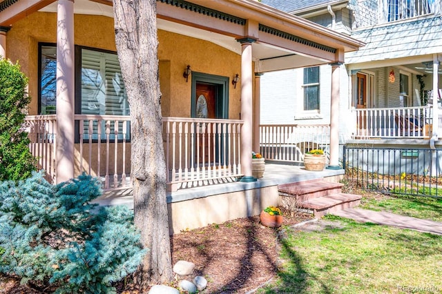 entrance to property featuring covered porch and stucco siding