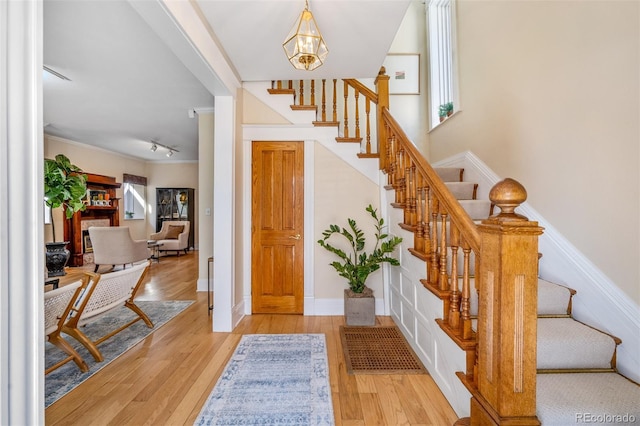 entrance foyer featuring stairs, wood finished floors, a chandelier, baseboards, and crown molding