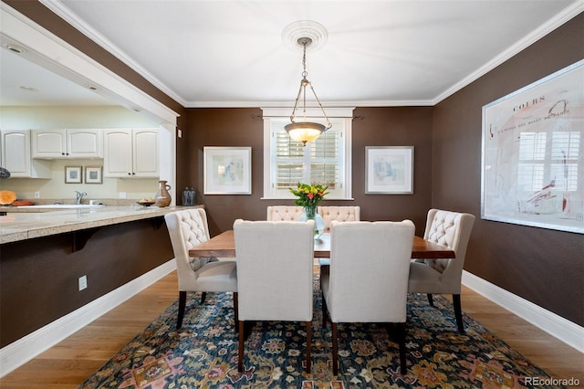 dining room with baseboards, wood finished floors, and crown molding