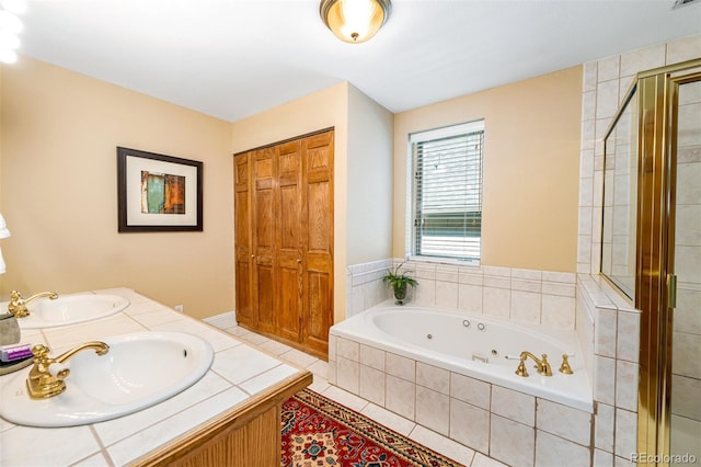 full bathroom featuring a sink, a whirlpool tub, a stall shower, and tile patterned floors