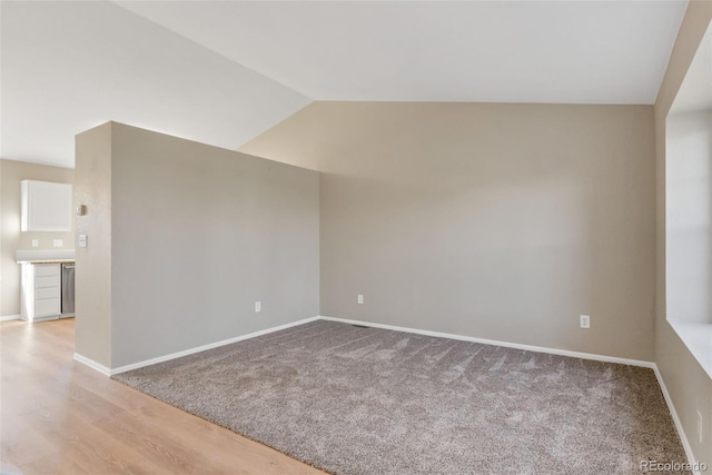 carpeted spare room with vaulted ceiling