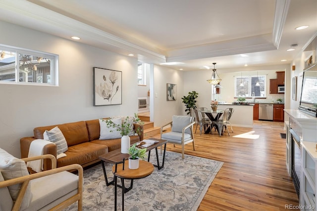 living room featuring a healthy amount of sunlight, a tray ceiling, and light hardwood / wood-style flooring