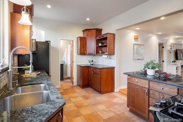 kitchen featuring tasteful backsplash, dark stone countertops, sink, and pendant lighting