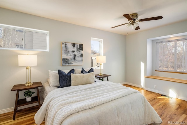 bedroom featuring multiple windows, ceiling fan, and light hardwood / wood-style flooring