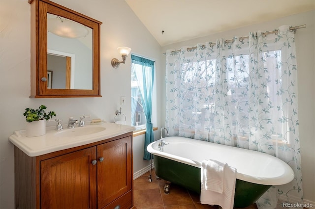 bathroom featuring tile patterned flooring, a tub to relax in, vanity, and vaulted ceiling