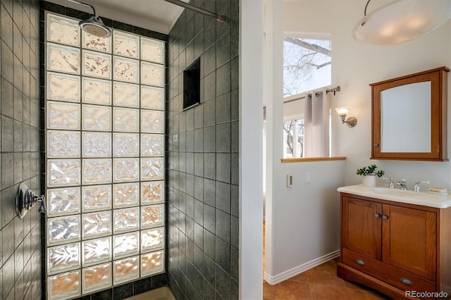 bathroom featuring tile patterned flooring, vanity, and a tile shower