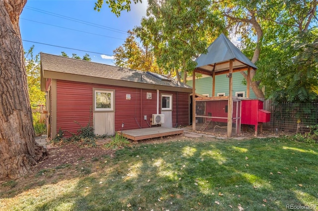 back of house with an outdoor structure, a lawn, and ac unit