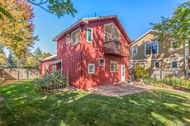 back of property featuring a balcony and a lawn