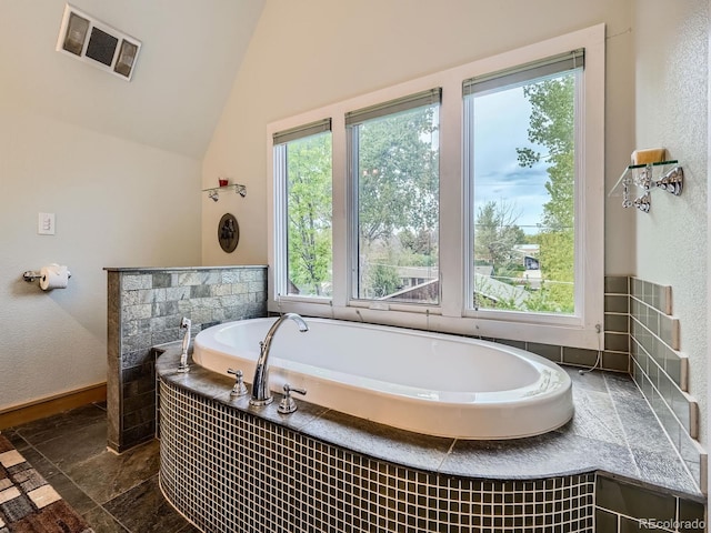 845 Urban St, Lakewood, CO 80401 - full bath with stone tile flooring, healthy amount of natural light, a garden tub, and vaulted ceiling