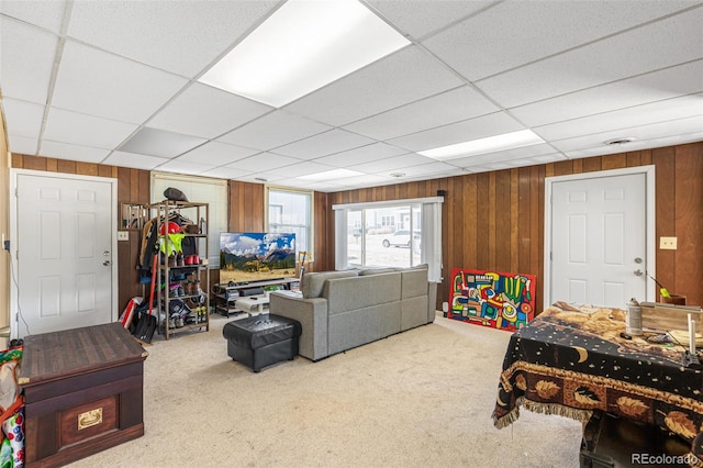 carpeted living room with a paneled ceiling and wooden walls