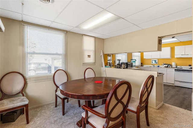 dining space with light carpet and a paneled ceiling