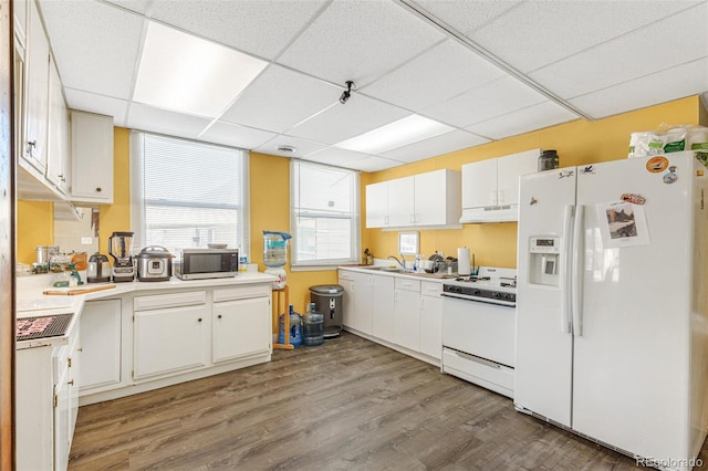 kitchen featuring white appliances, wood-type flooring, white cabinetry, sink, and a paneled ceiling