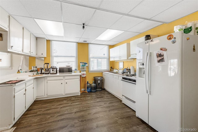 kitchen with white appliances, white cabinetry, sink, dark hardwood / wood-style flooring, and a paneled ceiling