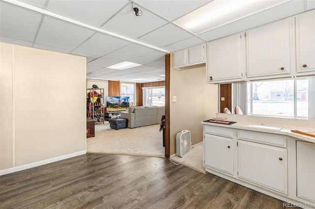 kitchen with a paneled ceiling, white cabinetry, and dark hardwood / wood-style floors