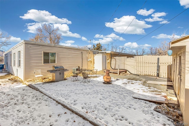 snow covered back of property featuring fence and a fire pit