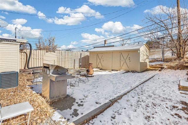 yard layered in snow featuring a storage shed