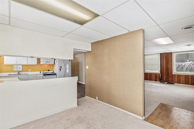 kitchen featuring white electric range oven, light carpet, white cabinets, a sink, and refrigerator with ice dispenser