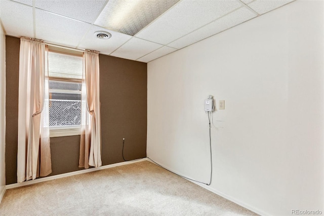 carpeted spare room featuring a paneled ceiling and visible vents