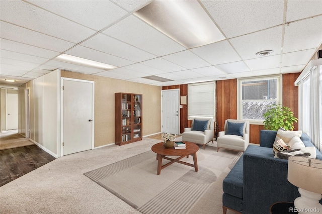 living room with a paneled ceiling, baseboards, visible vents, and carpet