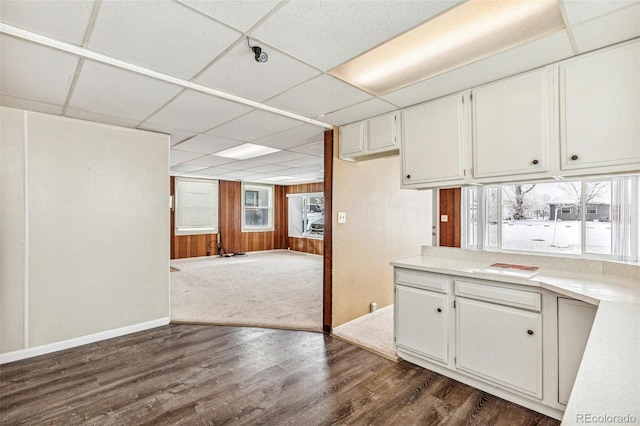 kitchen featuring baseboards, white cabinets, a drop ceiling, dark wood-type flooring, and light countertops