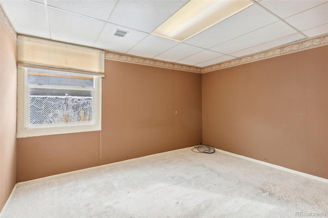 spare room featuring carpet floors, a drop ceiling, visible vents, and baseboards