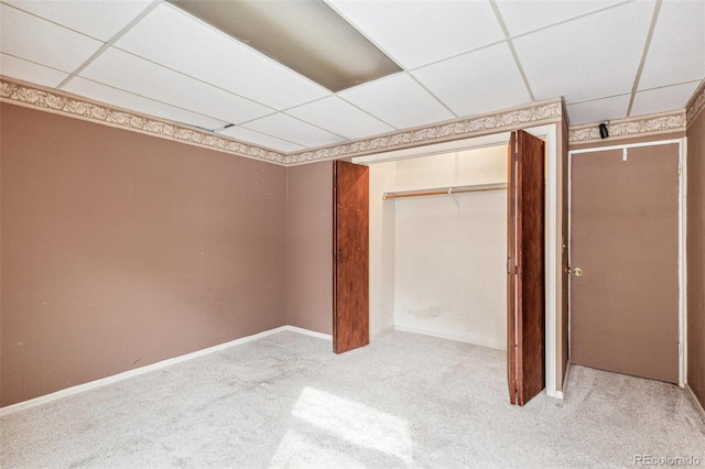 unfurnished bedroom featuring light carpet, a closet, a paneled ceiling, and baseboards